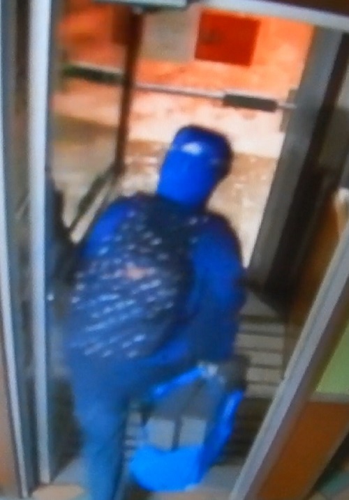 Le suspect qui porte un manteau d’hiver bleu et qui transporte un sac à dos bleu ainsi qu’un autre sac de la même couleur contenant les deux caisses enregistreuses volées.